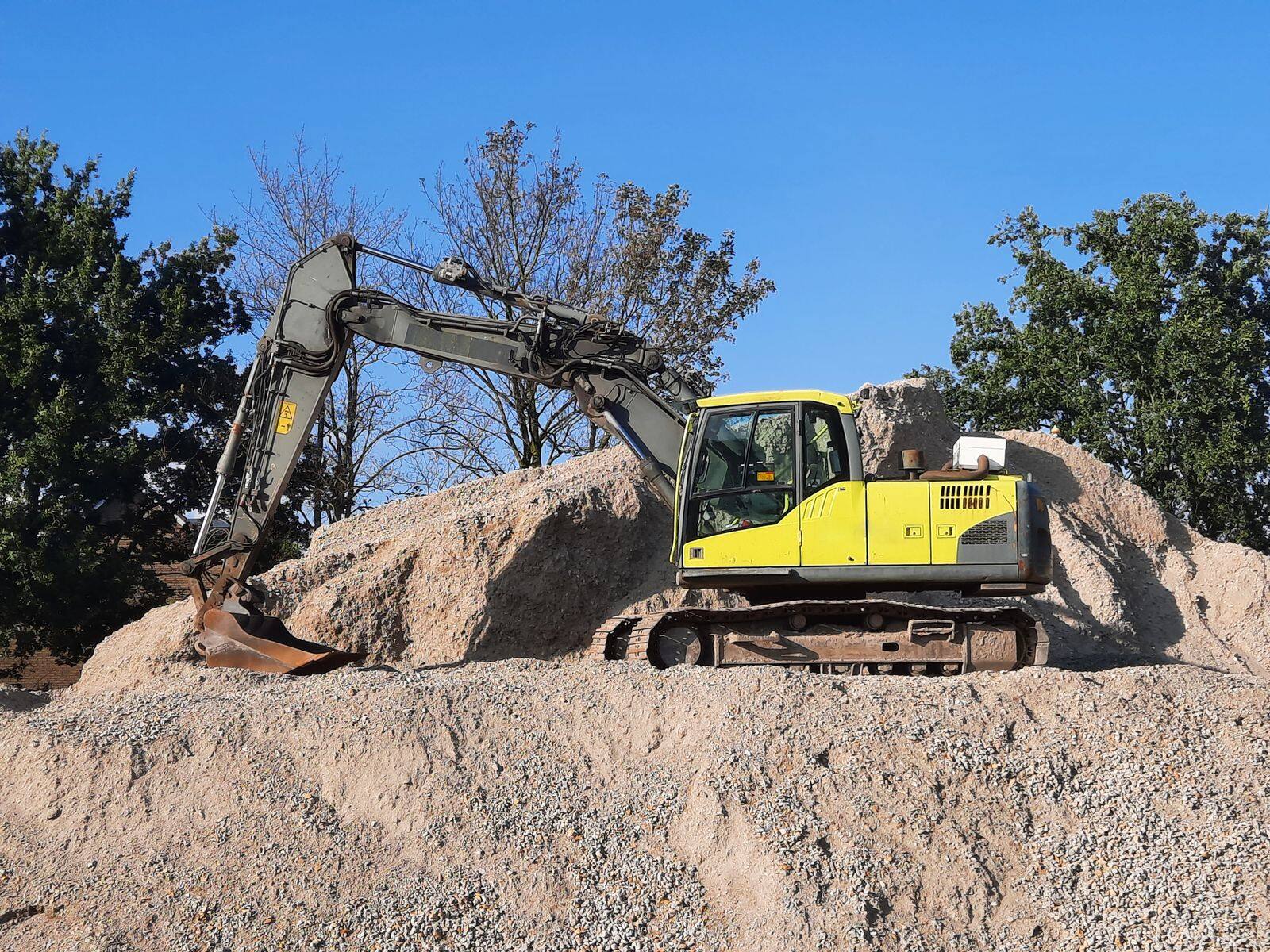 A yellow excavator sitting on top of a pile of dirt